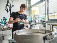 Ein Elektroniker für Geräte und Systeme arbeitet konzentriert an der Verschlauchung eines Industrieroboters.