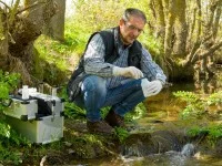 Eine Fachkraft für Wasserwirtschaft entnimmt Proben zur Überprüfung der Wasserqualität eines Flusses.