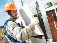 Ein Fassadenmonteur befestigt Fassadenteile an einem Gebäude.