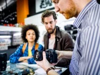 Ein Fotomedienfachmann erklärt Kunden die Funktionsweise einer Spiegelreflexkamera.