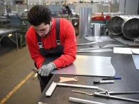 Ein Industrie-Isolierer schneidet einen Blechbogen für eine Isolierung zu.