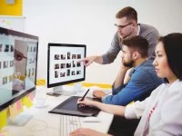 Eine Kauffrau für audiovisuelle Medien bearbeitet eine Bilddatei mit einem Grafiktablett.