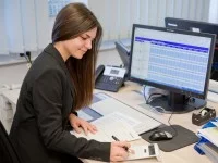 Eine Kauffrau für Kurier-, Express- und Postdienstleistungen berechnet die Kosten für Liefertouren beim Paketdienstleister Hermes.