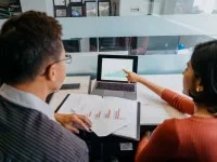 Zwei Kaufleute für Marketingkommunikation besprechen die Auswertung einer Marktforschung.