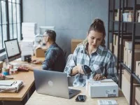 Eine Kauffrau im E-Commerce bereitet ein Päckchen für den Versand vor.