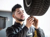 Ein Mechaniker für Reifen- und Vulkanisationstechnik überprüft das Profil eines Autoreifens.