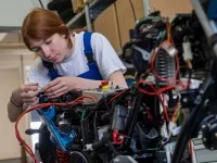 Eine Mechatronikerin repariert ein Motorrad.
