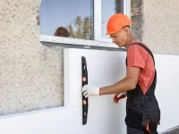 Ein Isolierfacharbeiter prüft die Dämmung des Hauses mit einer Wasserwaage.