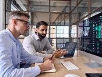 Zwei Kaufmänner für Digitalisierungsmanagement diskutieren Statistiken zu den Finanzen des Unternehmens.