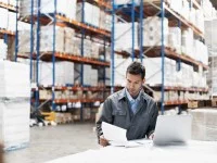 Ein Kaufmann für Spedition und Logistikdienstleistung überprüft die Lieferpapiere einer Warenlieferung.