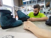 Ein Orthopädieschuhmacher prüft einen fertiggestellten orthopädischen Schuh.