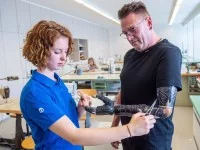 Eine Orthopädietechnik-Mechanikerin passt eine Armprothese an einem Patienten an.