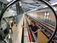 Eine Polster- und Dekorationsnäherin arbeitet an einer fast 30 Meter langen computergesteuerten Stickmaschine zur Fertigung von Gardinen der Marke Plauener Spitze.
