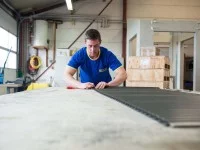 Ein Rollladen- und Sonnenschutzmechatroniker repariert in der Werkstatt einen Rollladen.