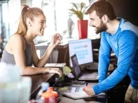 Ein Sport- und Fitnesskaufmann berät im Fitnessstudio eine Kundin.