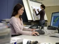 Eine Technische Systemplanerin erstellt am PC nach den Vorgaben der Konstrukteure mit einem CAD-Programm eine 3-D-Zeichung.