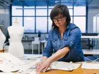 Eine Textil- und Modeschneiderin überträgt vor dem Zuschneiden das Muster auf den Stoff.