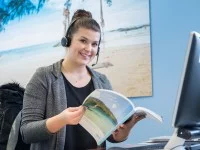 Eine Tourismuskauffrau für Privat- und Geschäftsreisen berät eine Kundin telefonisch.