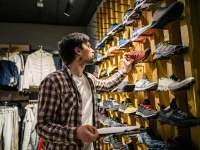 Ein Verkäufer macht in einem Sportgeschäft Inventur bei den Sportschuhen.