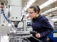 Eine Zerspanungsmechanikerin arbeitet an einer Werkzeugmaschine.